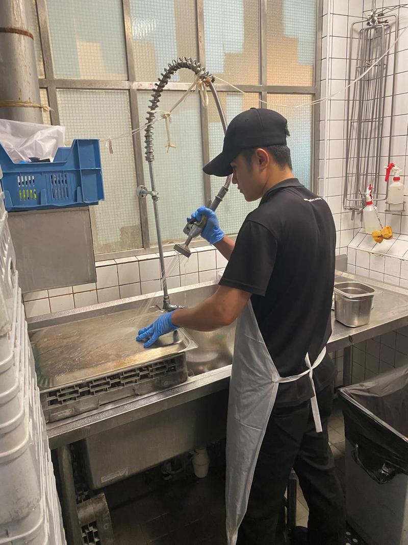 CleanLee dishwasher using a pre-rinse spray hose at a restaurant dishwashing station in Singapore
