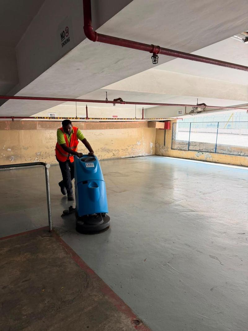 CleanLee operator using a walk-behind auto scrubber on a loading bay floor
